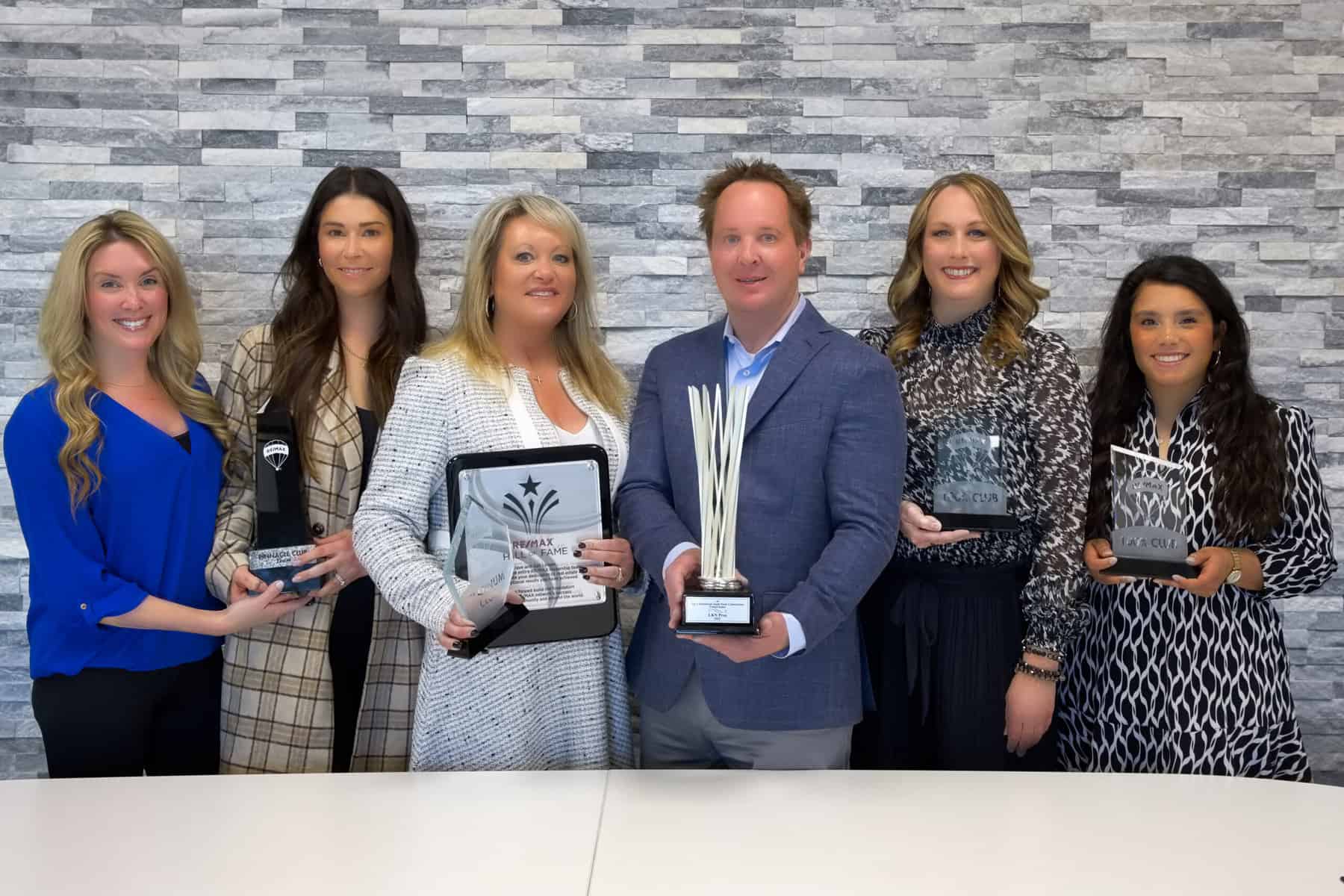 A group of people posing with awards in front of a table.