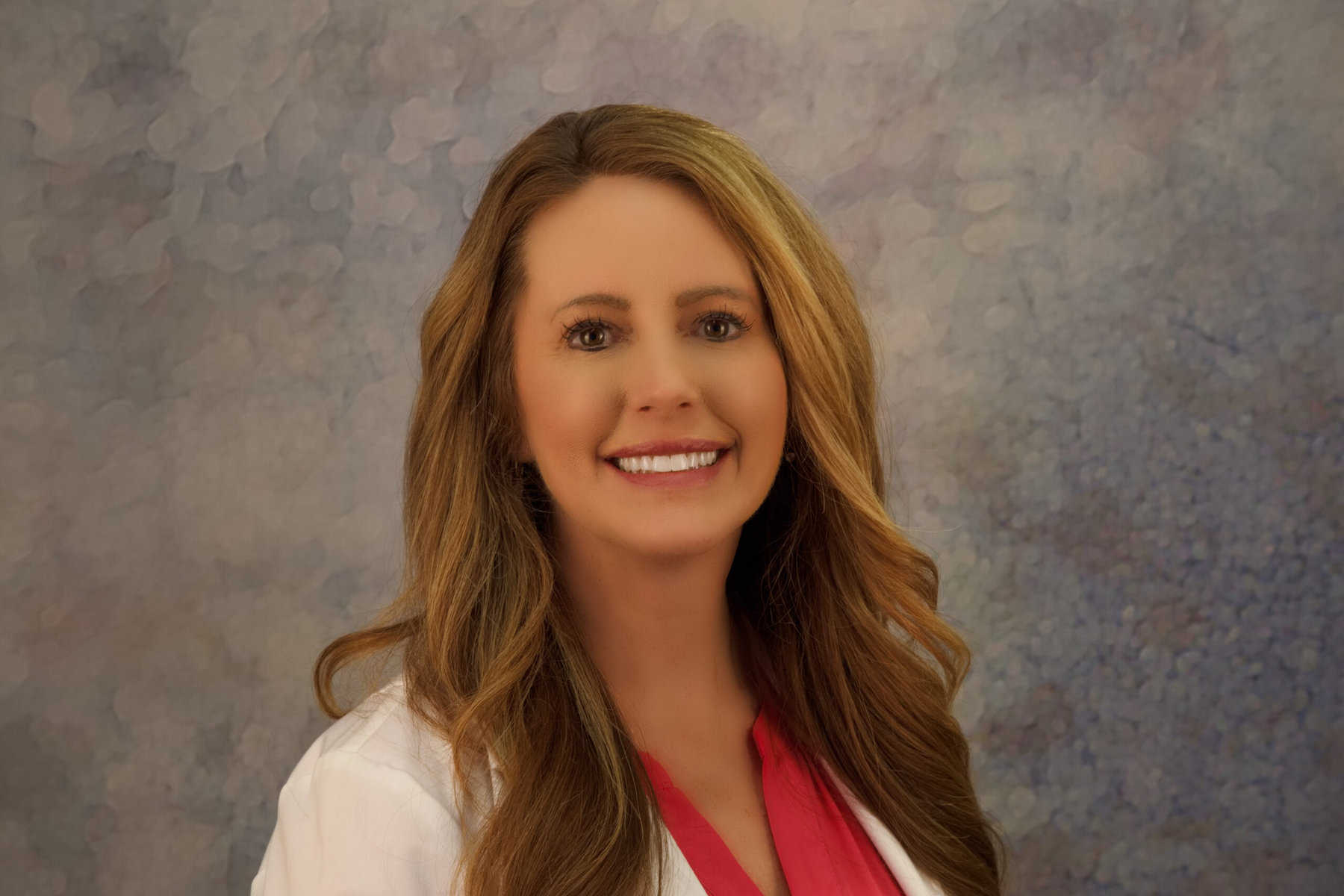 A woman in a white coat smiling for the camera.