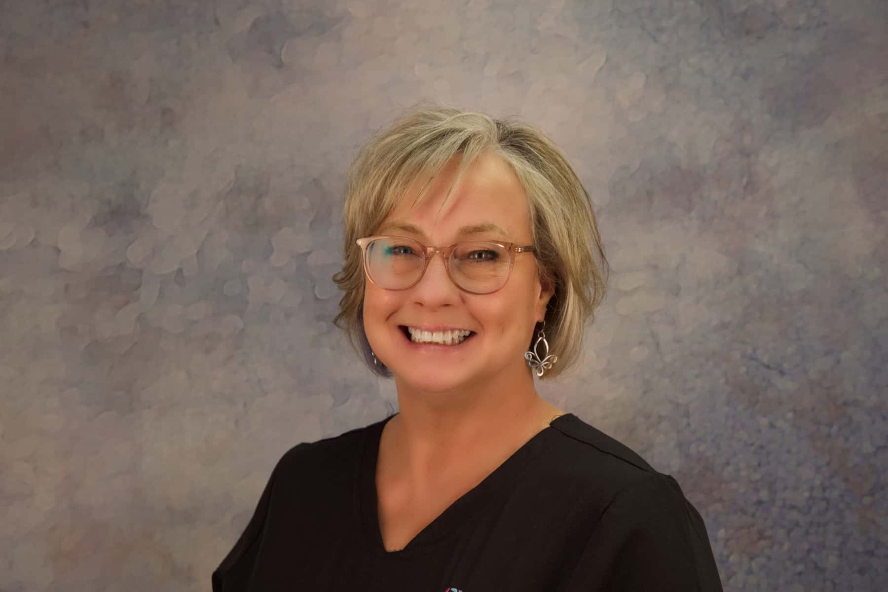 A woman in a black scrub top smiling for the camera.