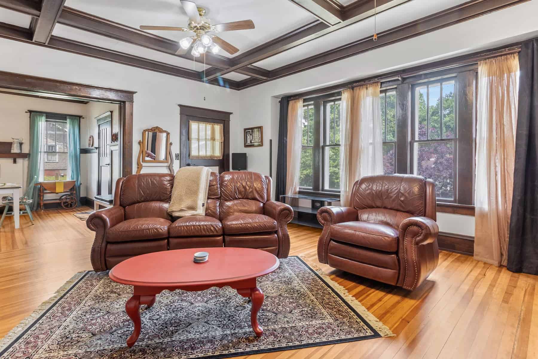 A living room with hardwood floors and brown leather furniture.