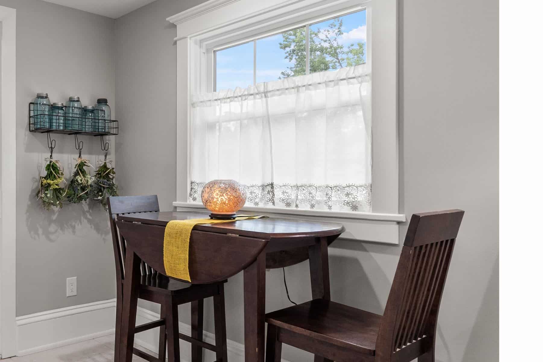 A small table with two chairs in front of a window.