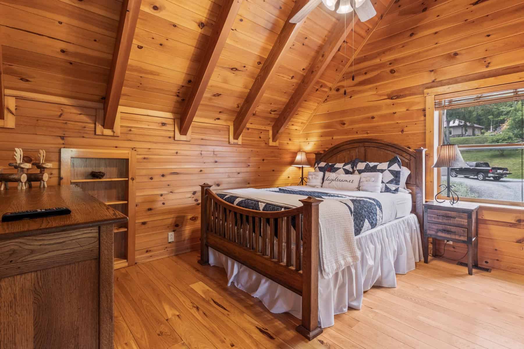 A bedroom in a log cabin with a bed and a desk.