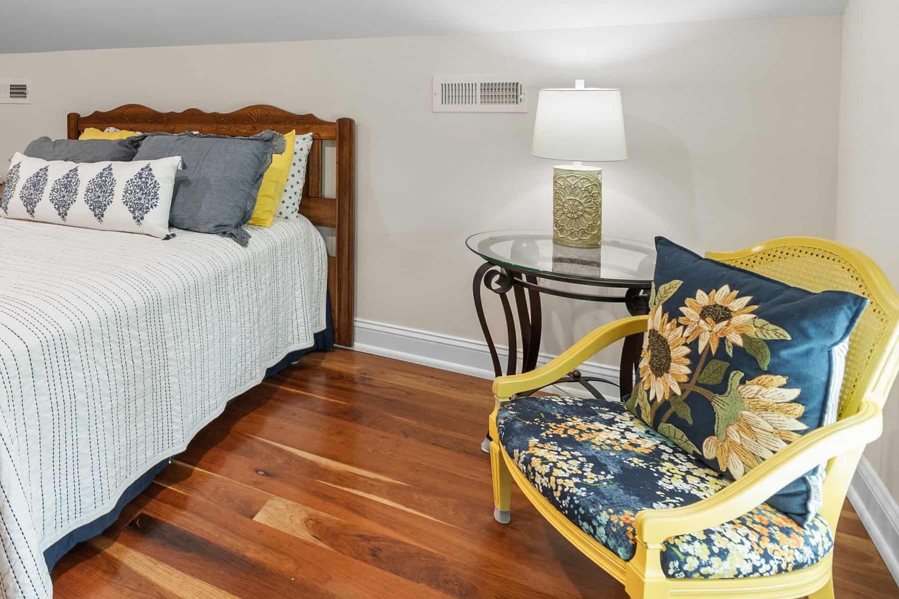 A bedroom with hardwood floors and a yellow chair.