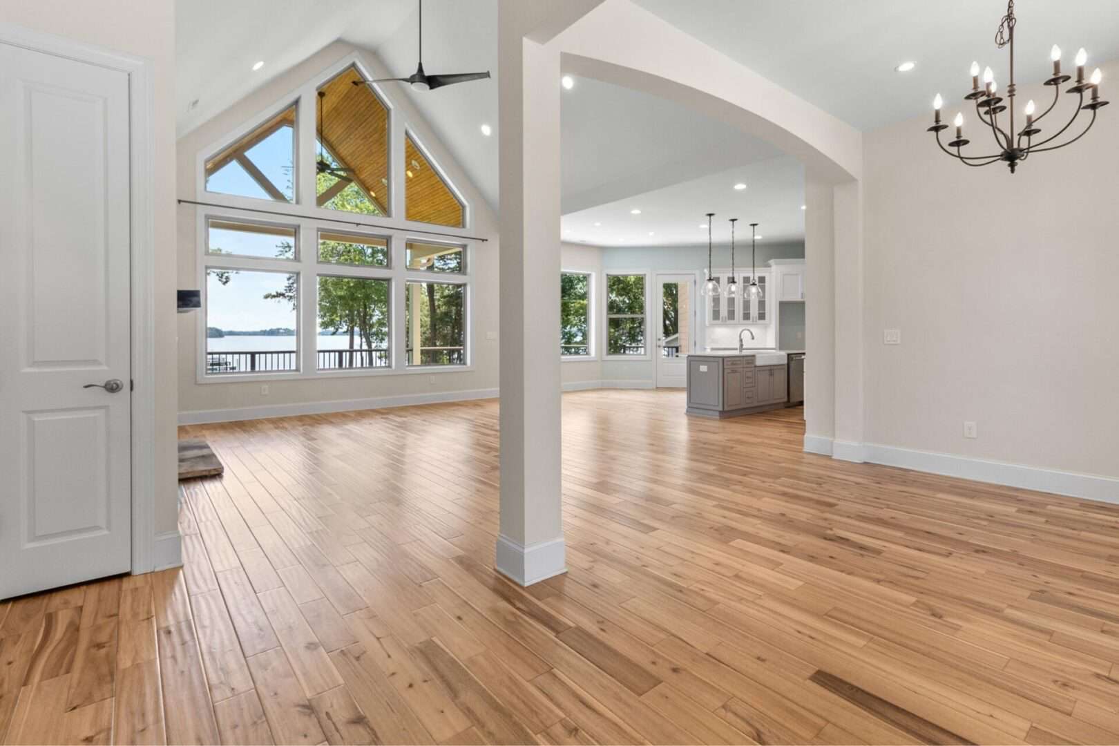 An empty living room with hardwood floors and a large window.