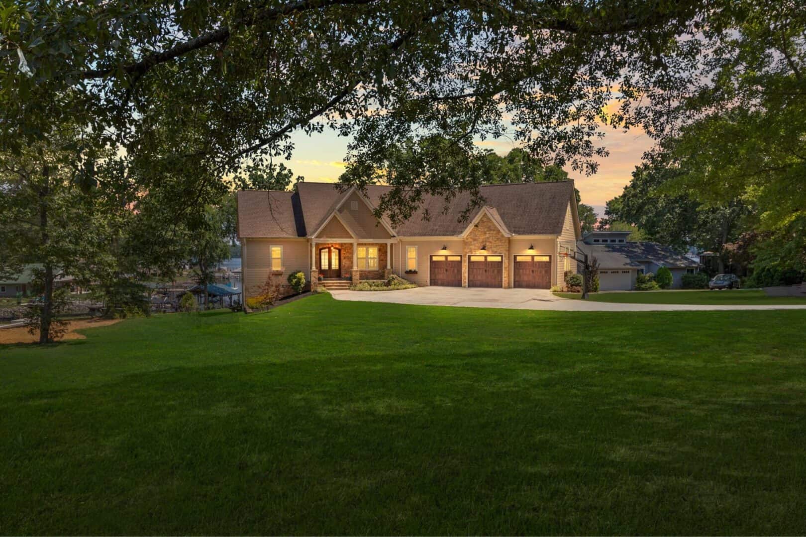 A home with a large lawn and trees at dusk.