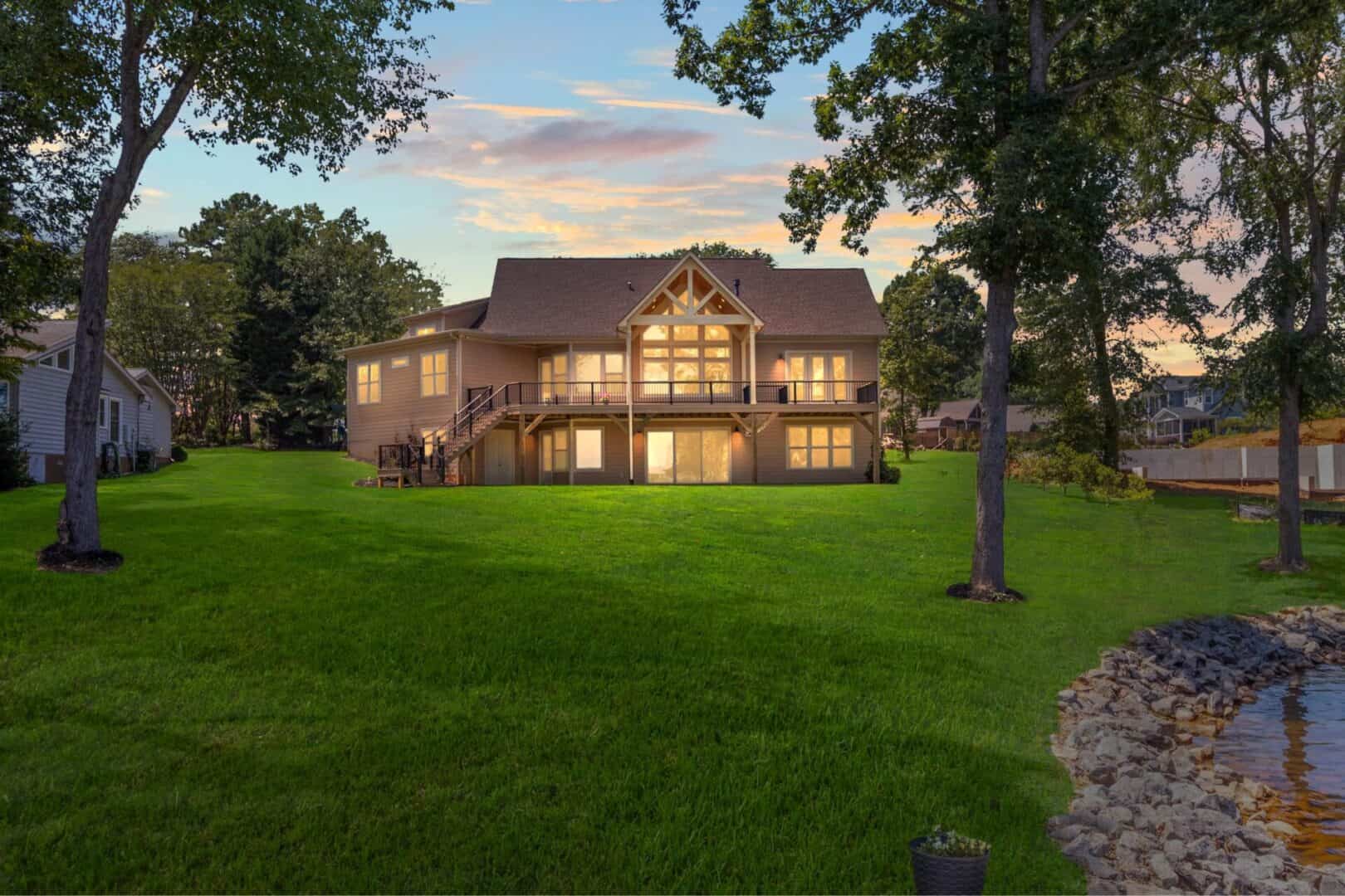 A home with a lake and grass in front of it.