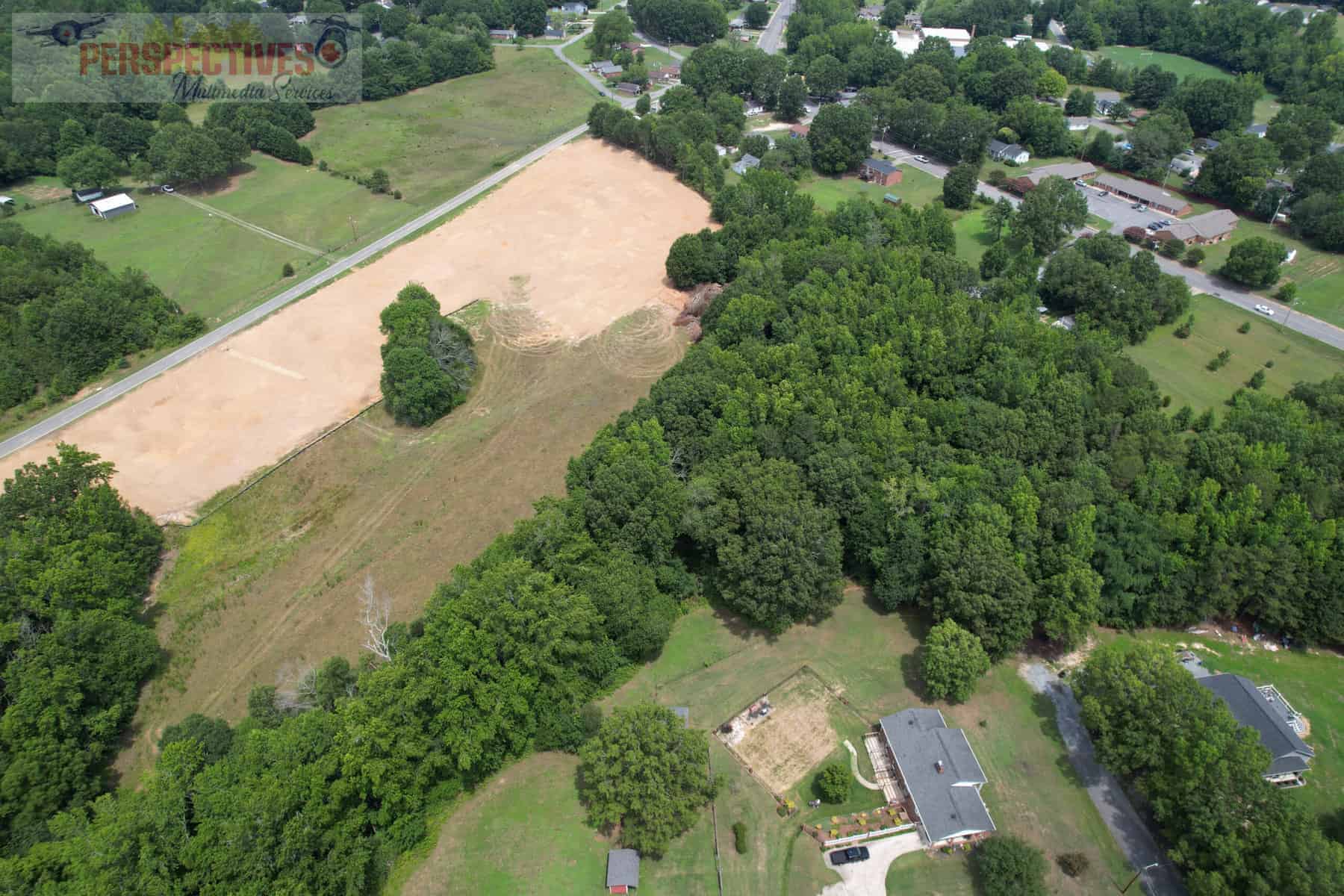 An aerial view of a vacant lot in a wooded area.