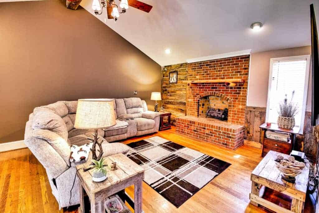 A living room with brick walls and a fireplace.