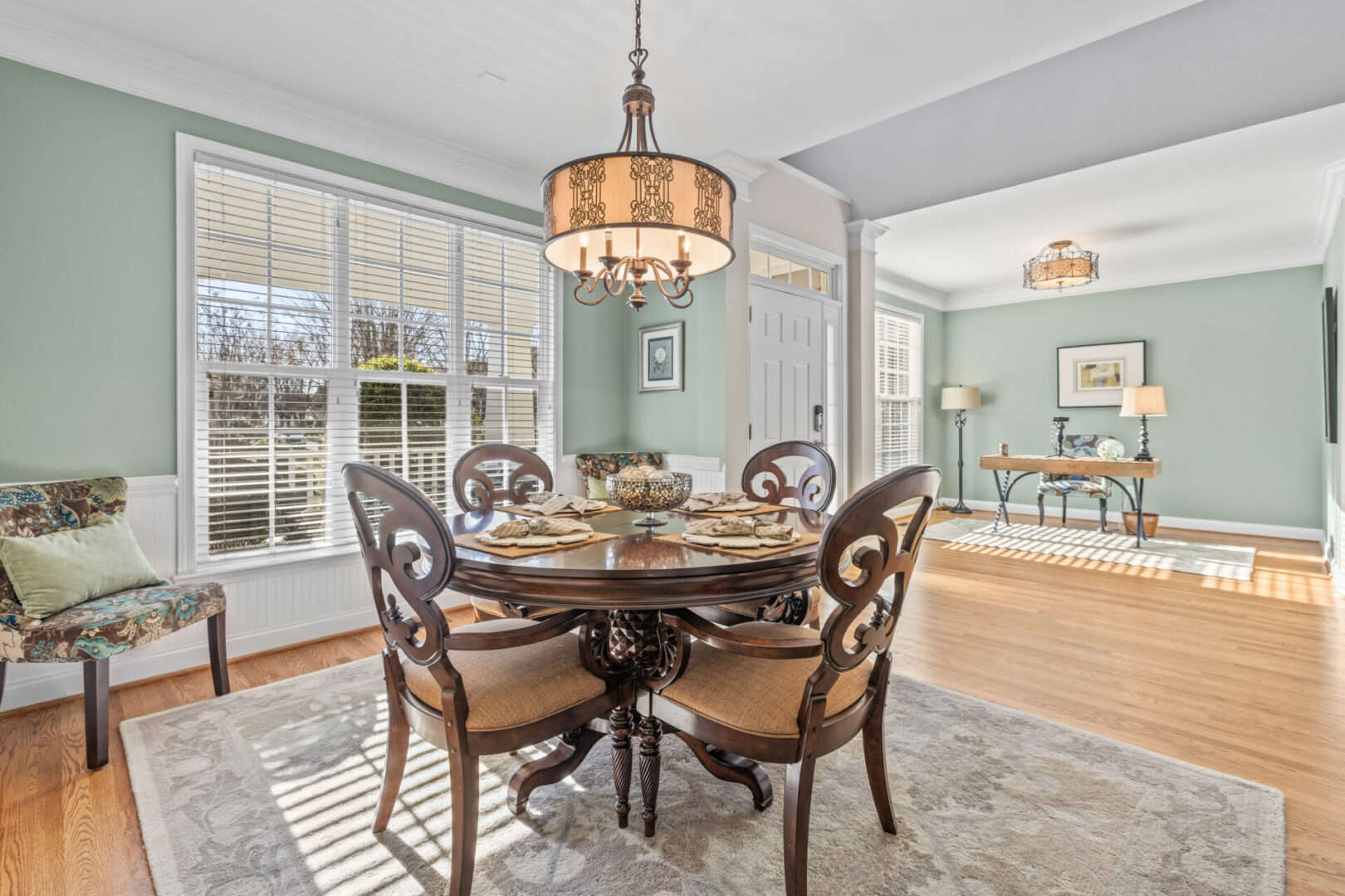 A dining room with green walls and hardwood floors.