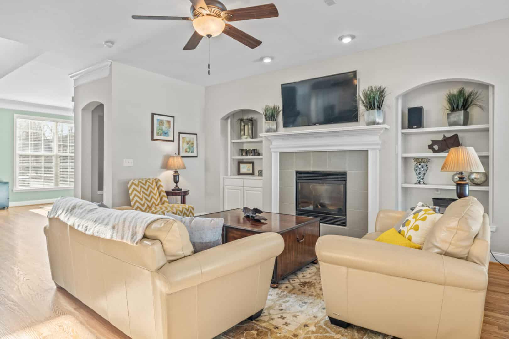 A living room with a fireplace and a ceiling fan.