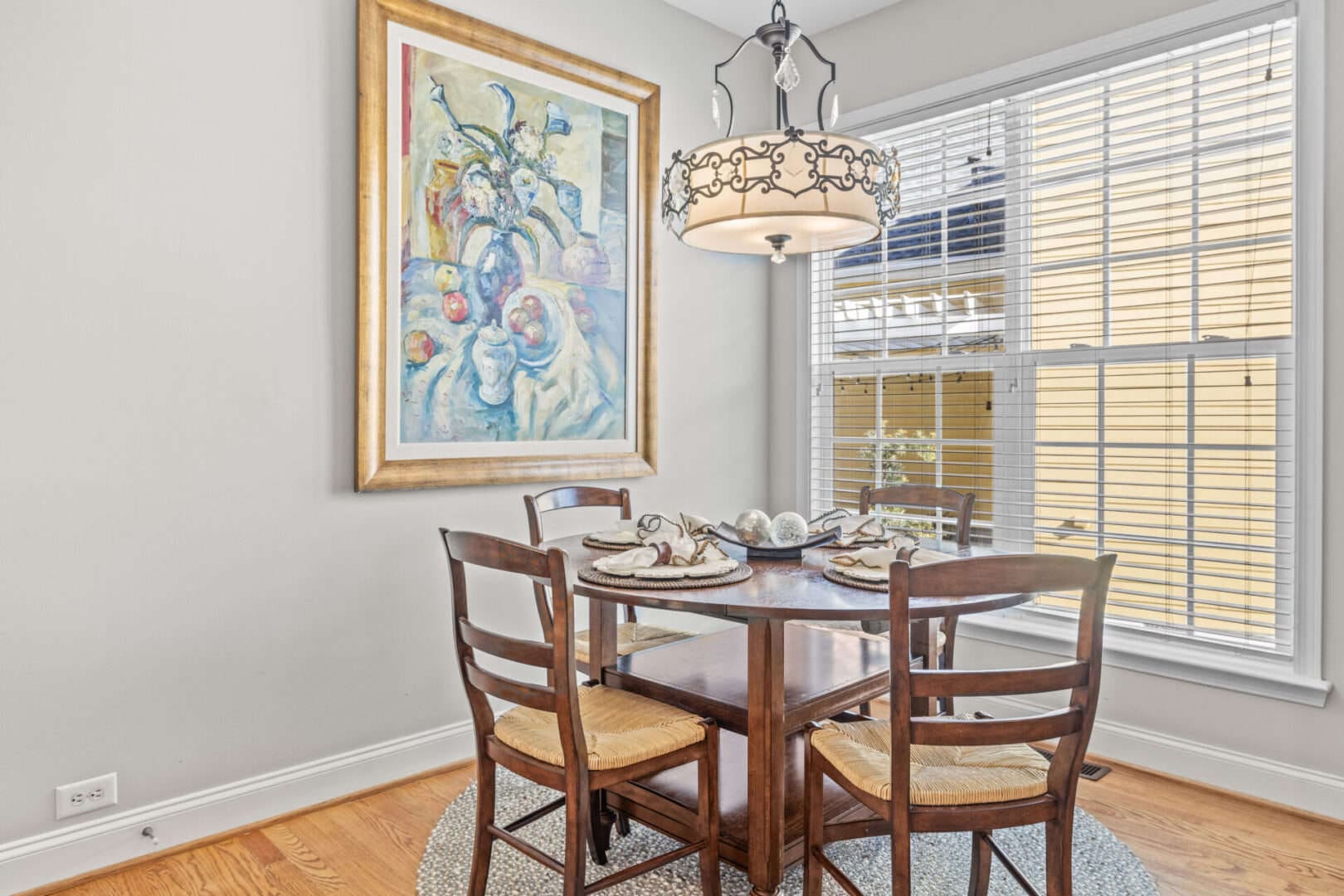 A dining room with a table and chairs and a painting.