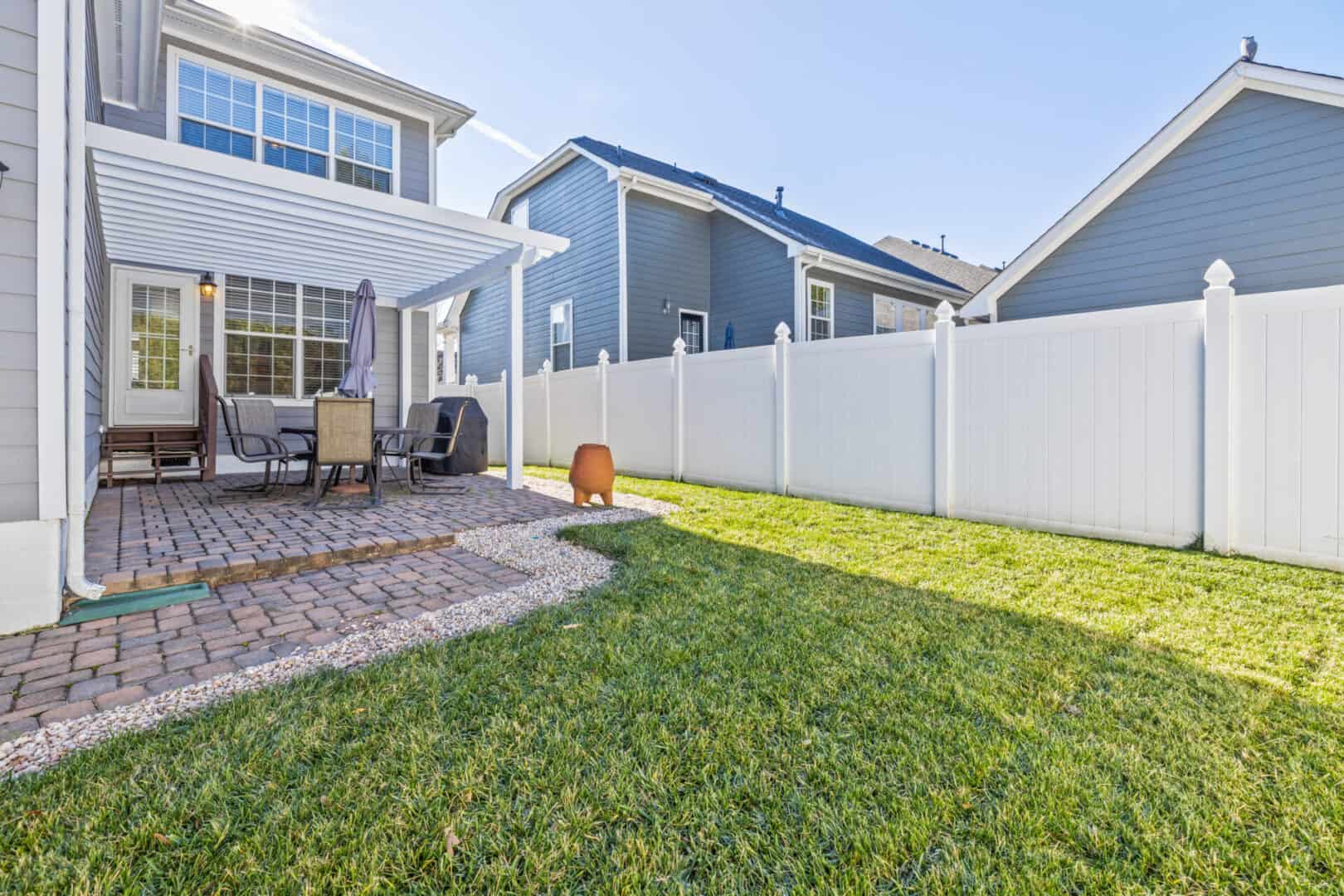 The backyard of a home with a white fence.