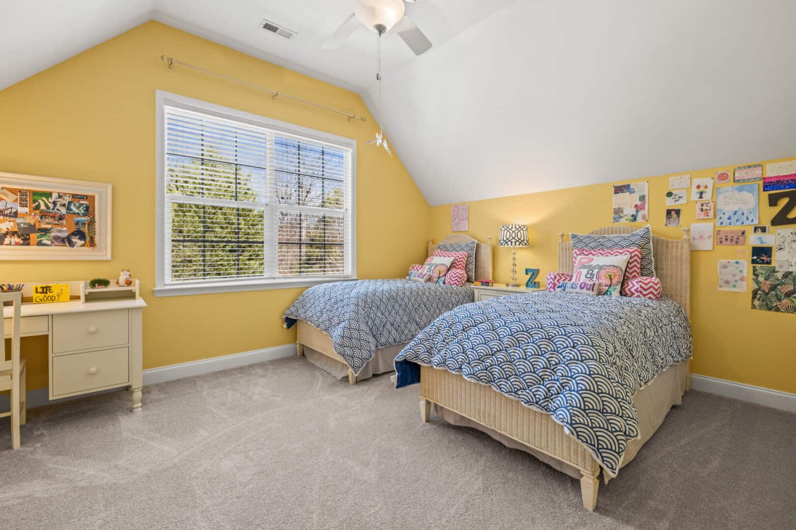 A yellow bedroom with two beds and a ceiling fan.